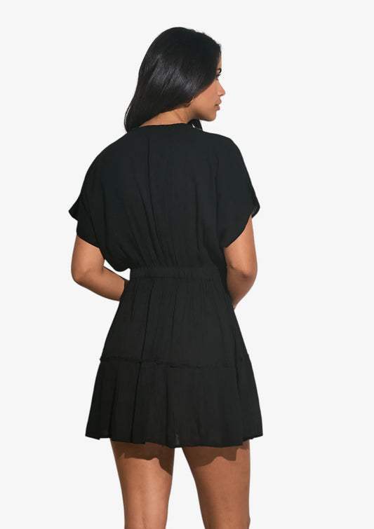Woman wearing black v-neck mini dress with short sleeves at Mimiluca Boutique.