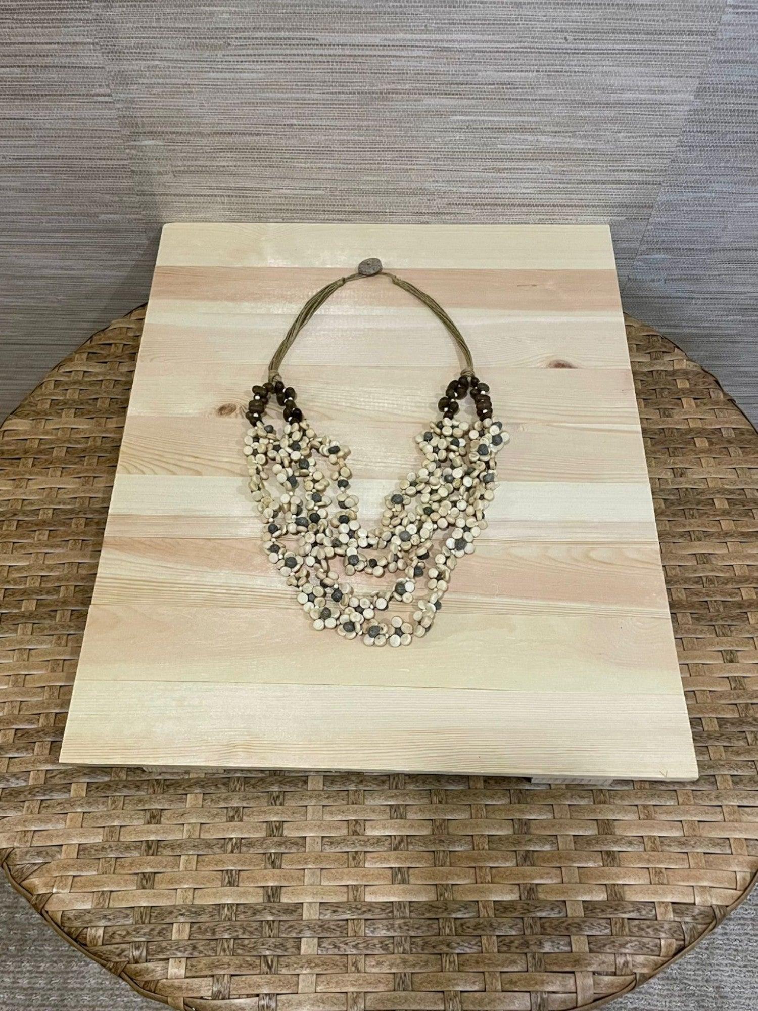 Necklace on wood and wicker table. Mimiluca Boutique.