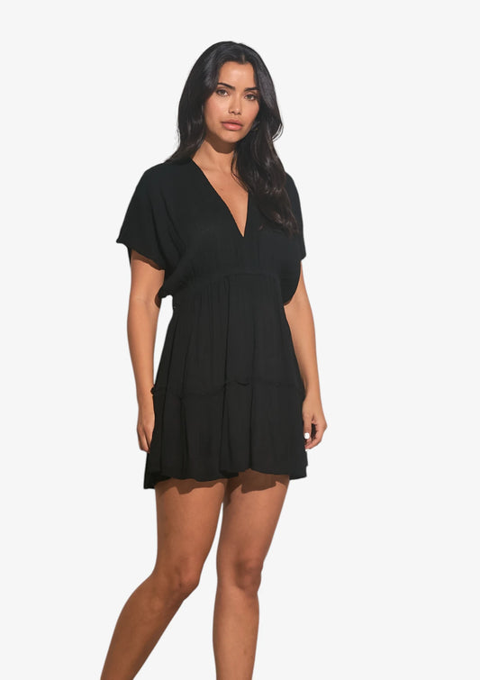 Woman wearing black v-neck mini dress with short sleeves at Mimiluca Boutique.